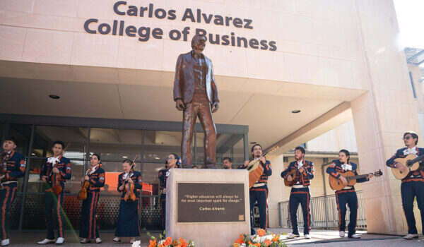 Mariachi musicians flank a bronze statue of Carlos Alvarez outside the Alvarez College of Business.