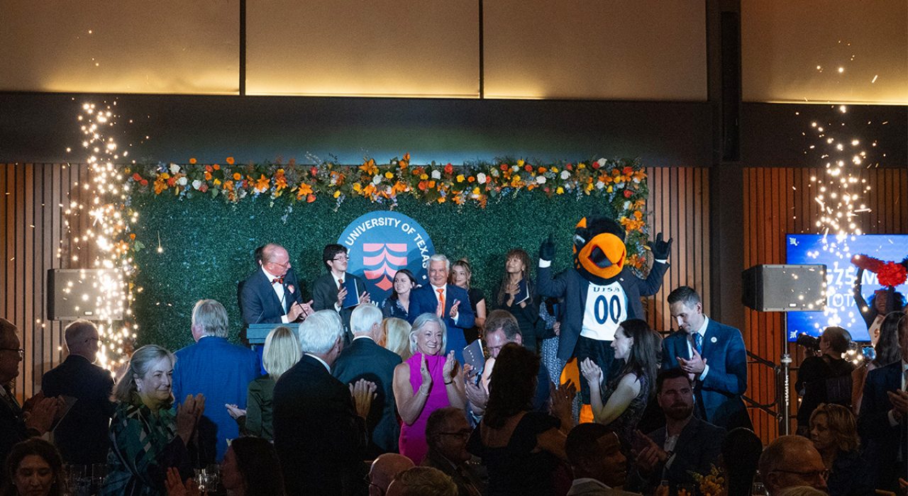 Fireworks illuminate on each side of a stage as people smile and clap.