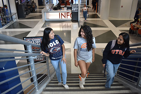 Three students walking up steps while talking