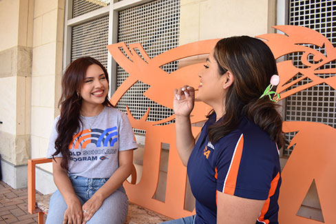 Two students talking while sitting on a bench