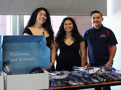 Three people in front of a table with swag