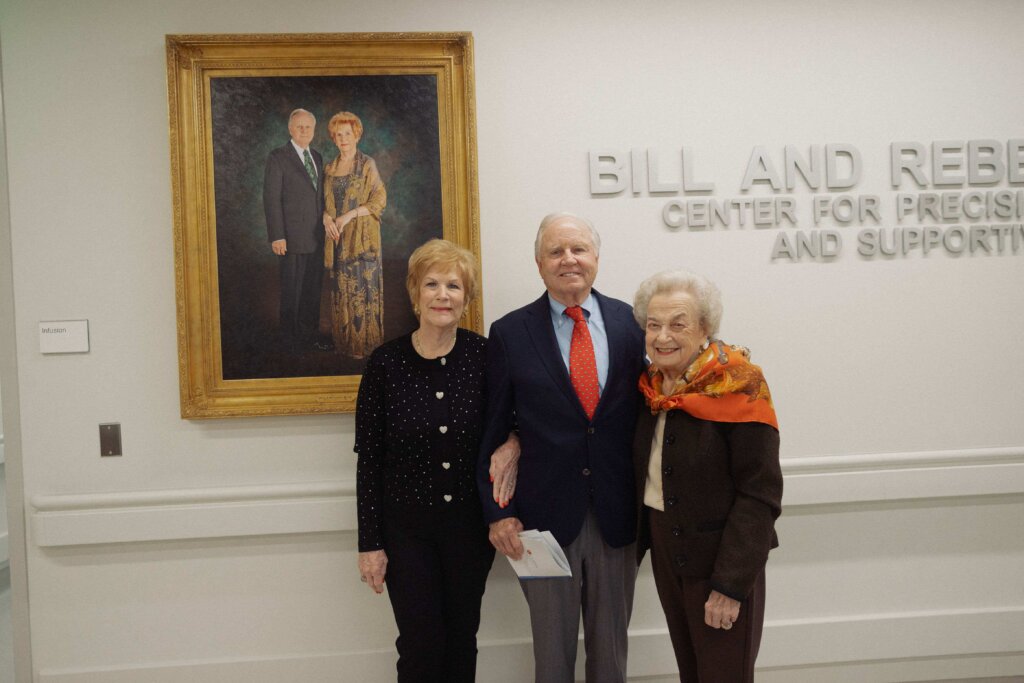Rebecca Reed, Bill Reed and Ann Biggs are shown in front of a portrait of the Reeds at the Biggs Institute