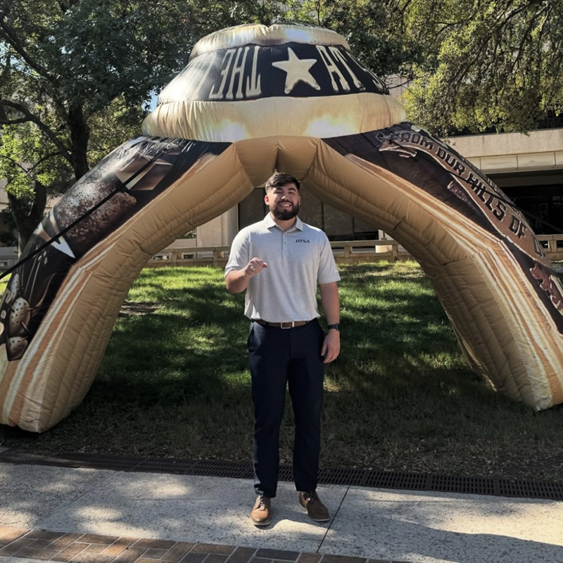 UTSA student showing ring in front of blow up ring