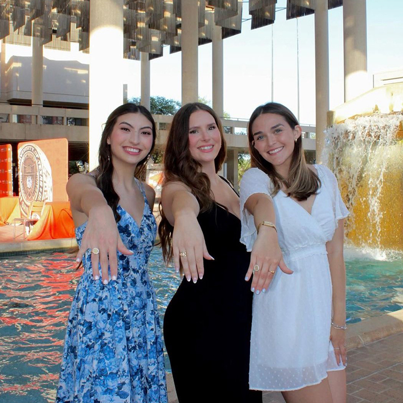 3 students showing off UTSA ring in Sombrilla Plaza