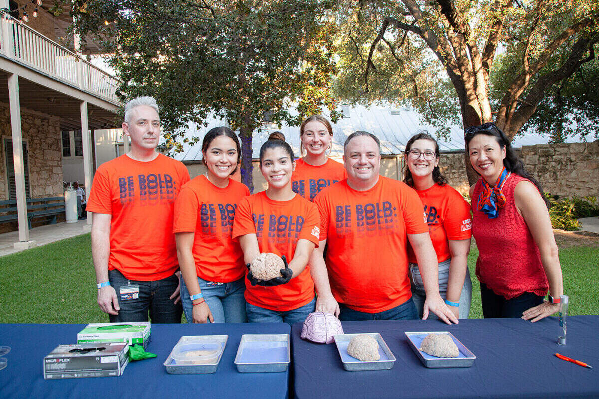 Several individuals stand together in front of a table.