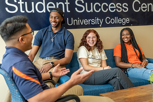 Group of four students talking and laughing in the University College Student Success Center