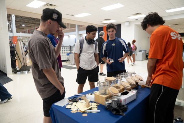 Students standing around a table selecting bath crystals and scented oils from various jars