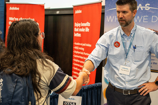 Student shaking hands with someone at an event
