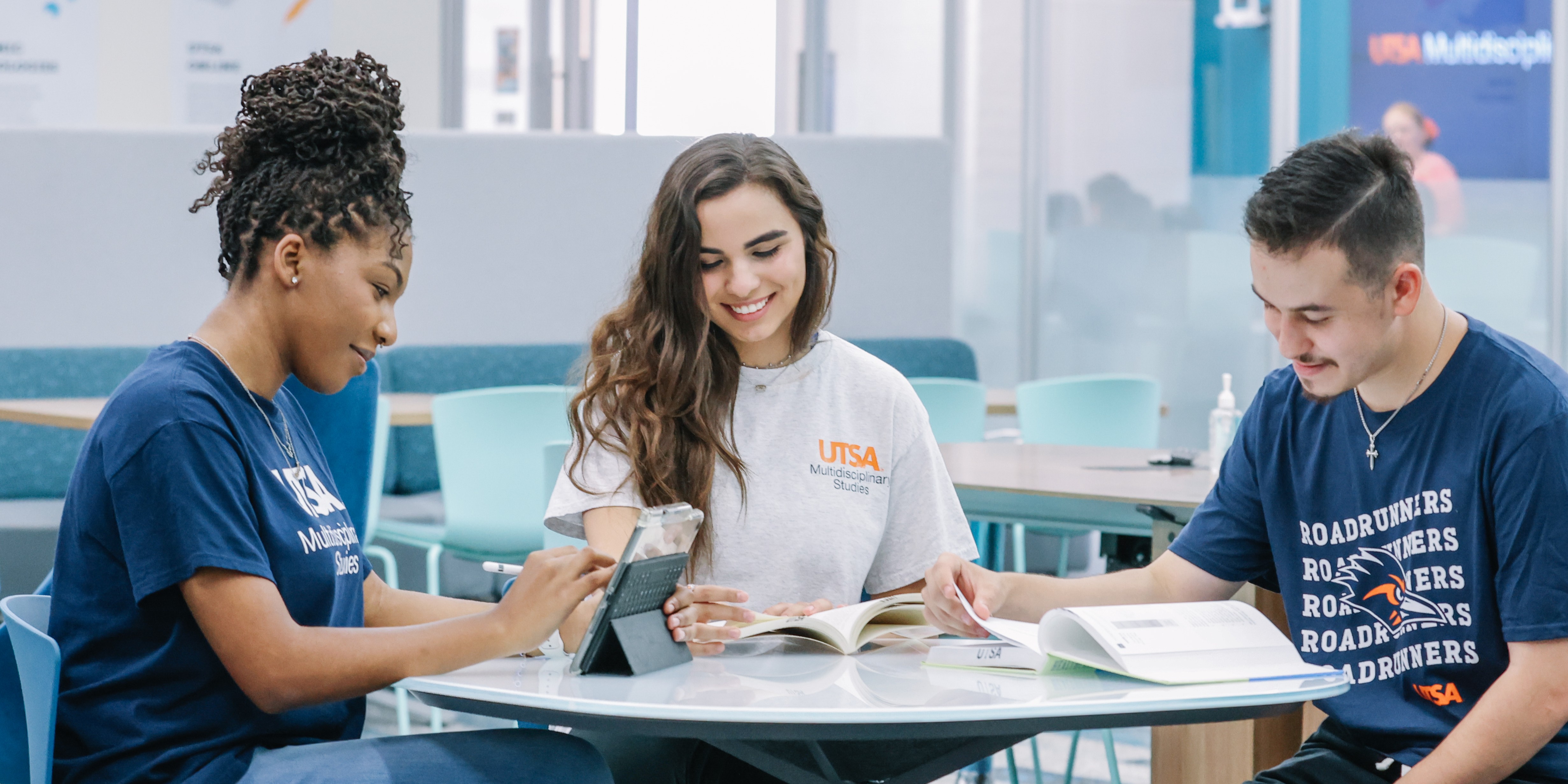 Three students studying and smiling at a table.