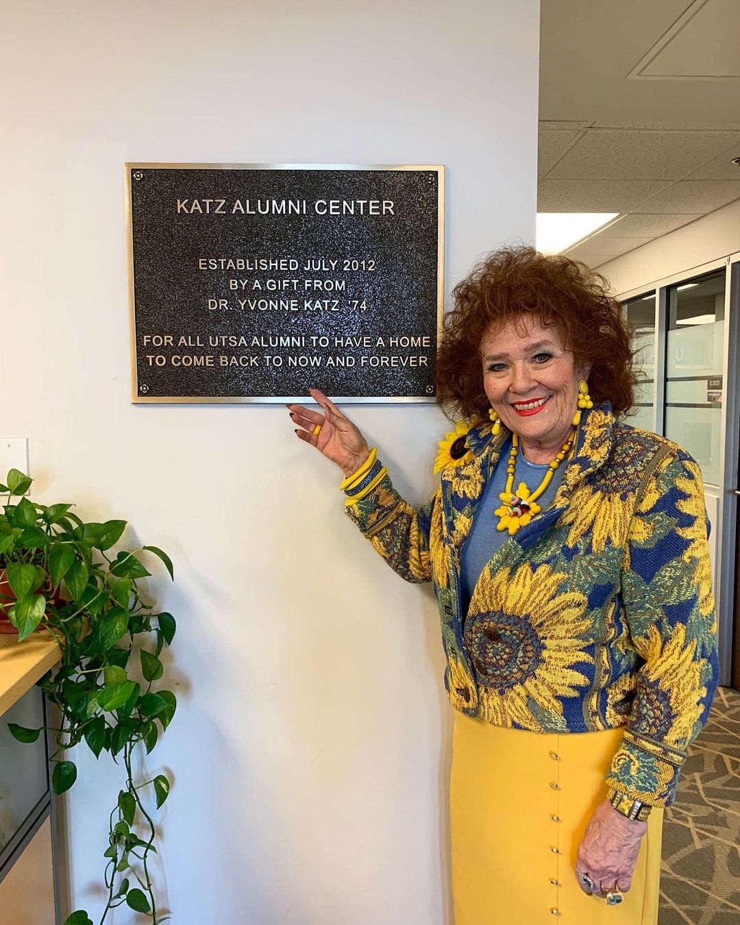 Yvonne Katz pointing to plaque at Katz Alumni Center