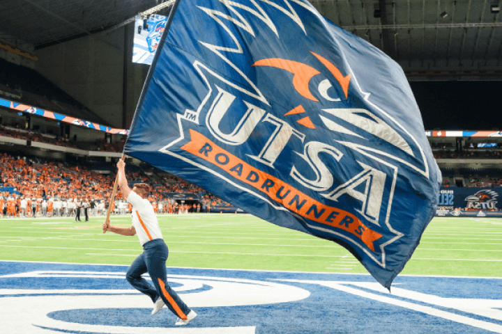 Student with the Rowdy Roadrunner flag running across the football field