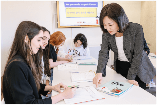 A teacher assists three students in a classroom setting.