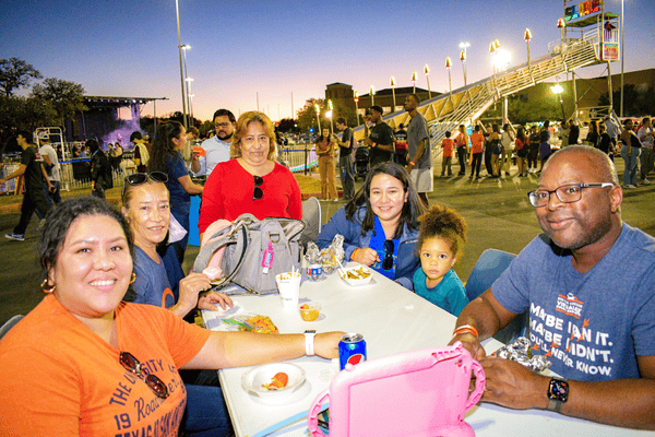 family eating food with stage and booths in the background