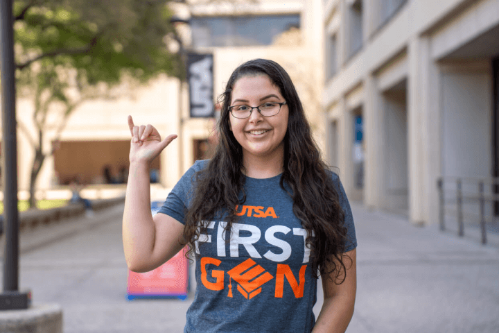 Young woman with long dark hair and glasses, wearing a 'First Gen' T-shirt