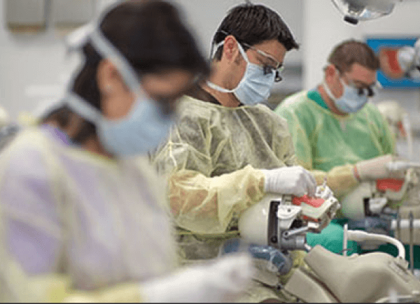 Dental students in protective gear, including masks and gowns.